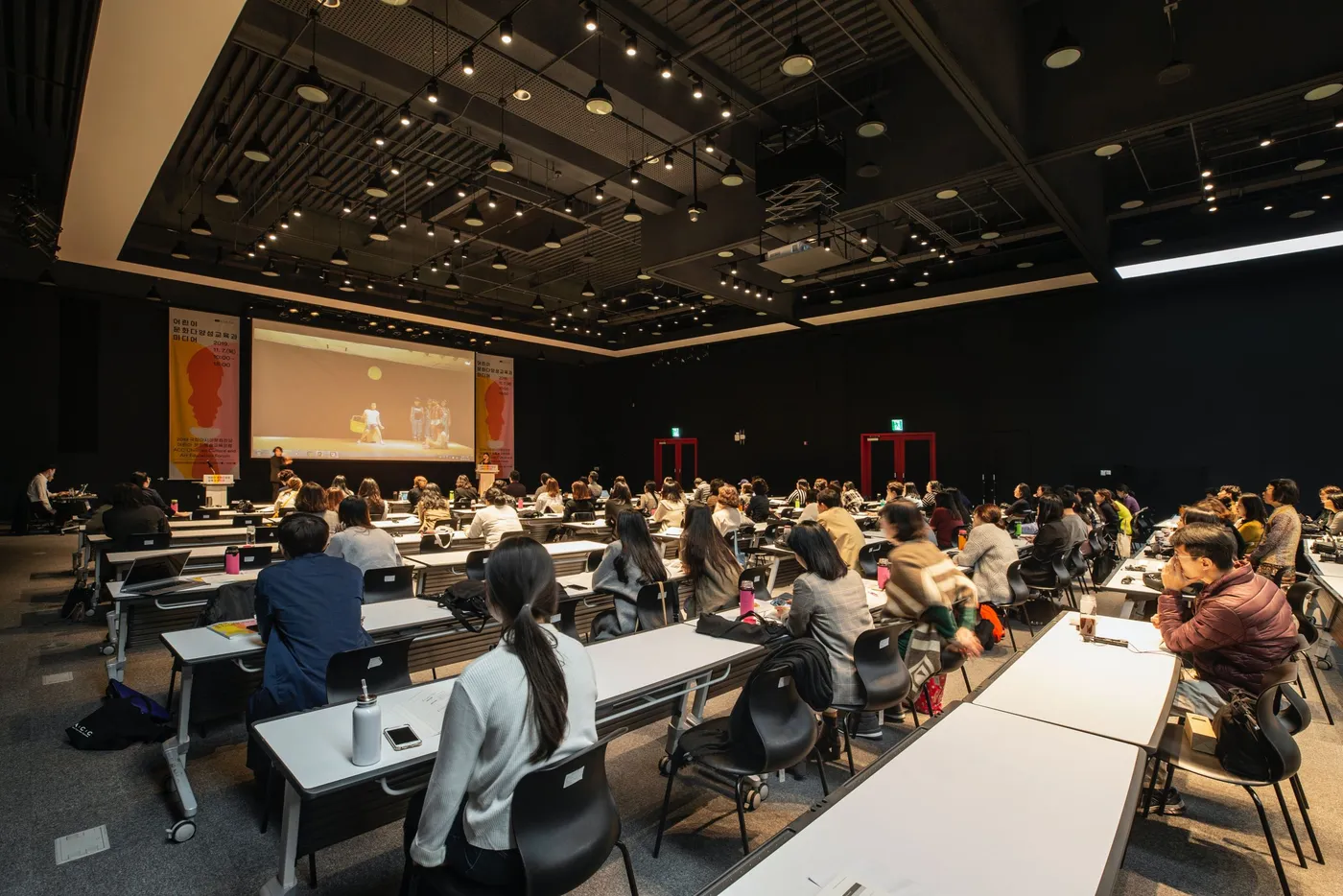 Attendees at classroom-style tables during a forum