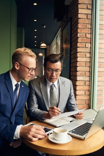 Two financial advisors reviewing documents and a laptop together