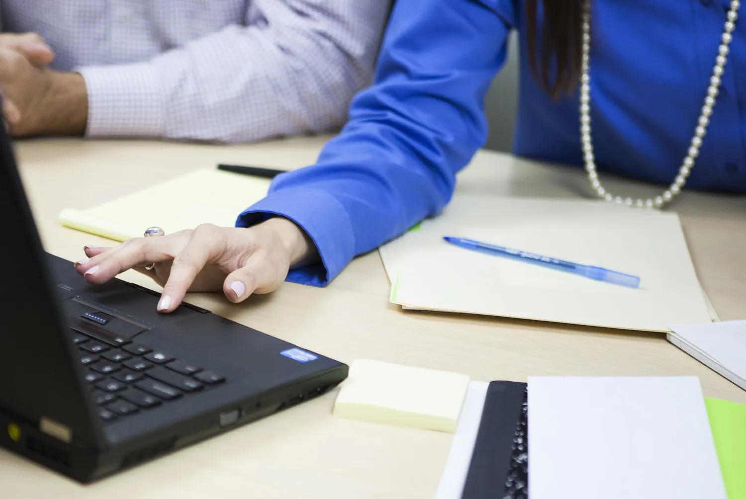 A linguist reviews translated text at a laptop beside printed drafts
