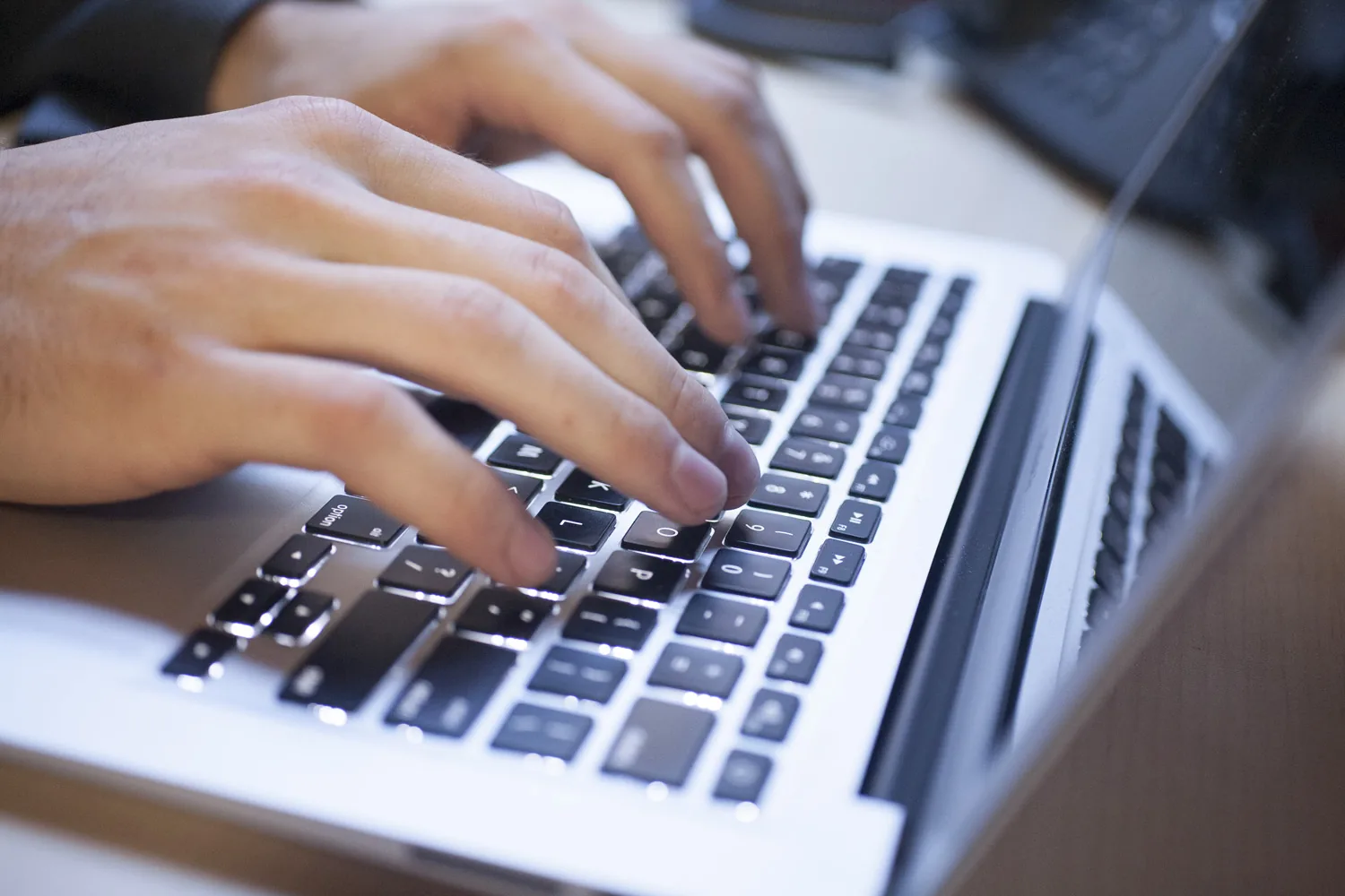 A linguist’s hands typing a transcript on a laptop
