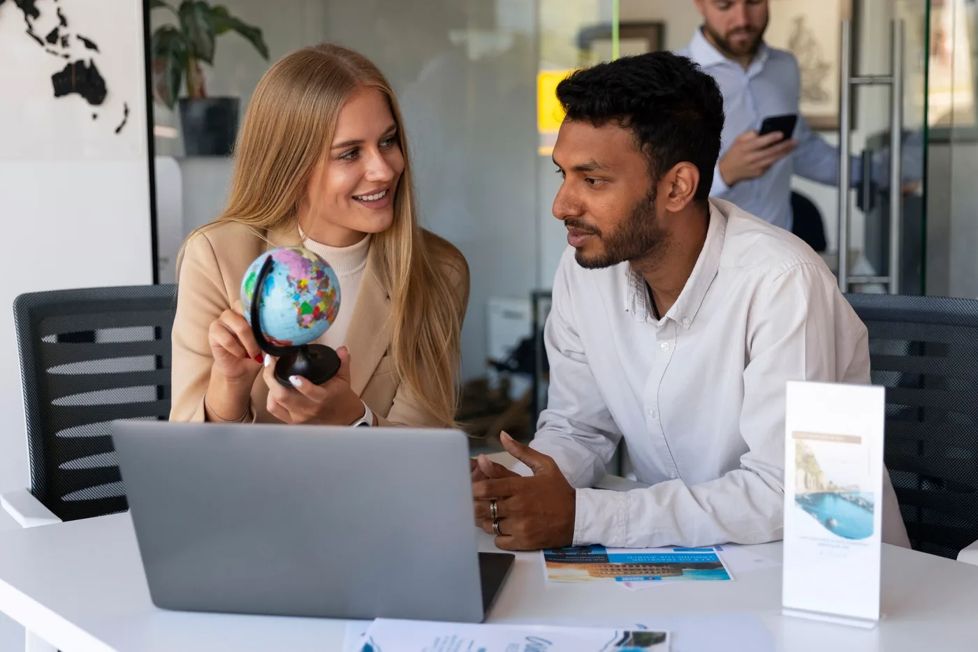 A travel advisor holding a globe while planning a trip with a client